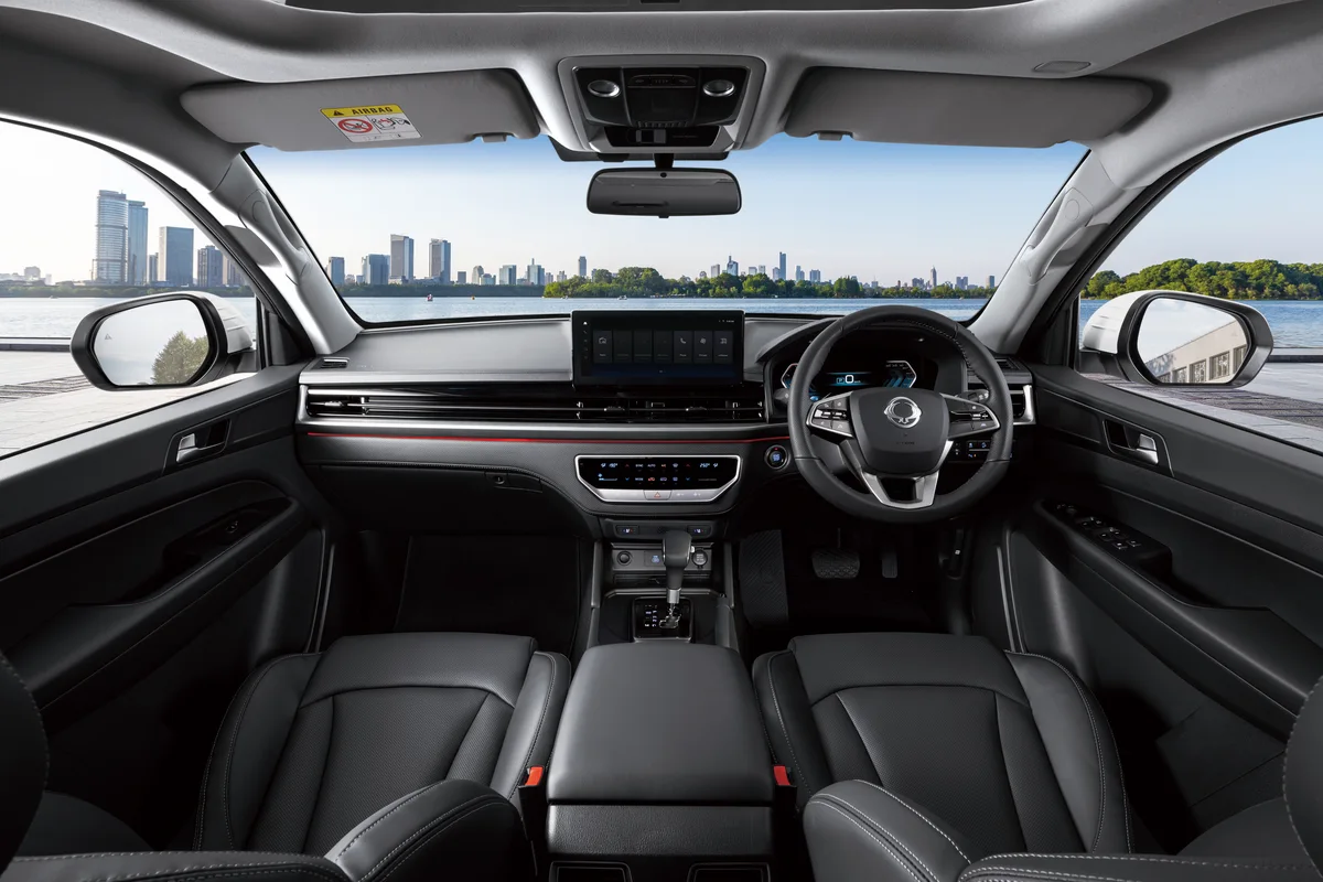 The black dashboard and right-hand-drive steering wheel of a KGM Musso