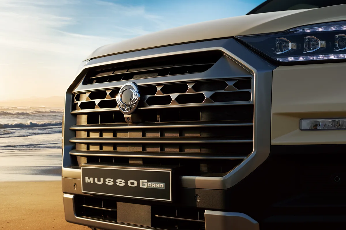 The chrome grille and MUSSO GRAND plate of a Sandstone Beige KGM Musso Grand