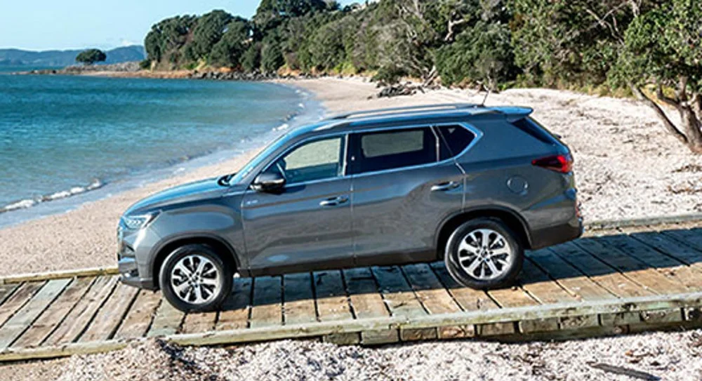 A grey KGM Rexton on a boardwalk above a beach