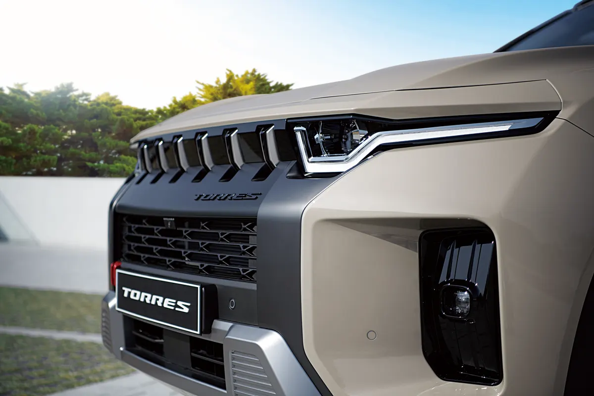 The LED headlights, slatted grille and TORRES plate of a Latte Greige KGM Torres