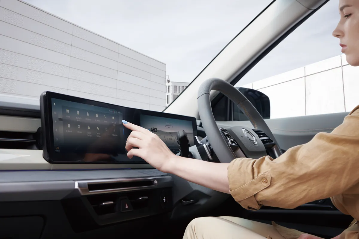 A hand using the wide touchscreen on the dashboard of a KGM Torres